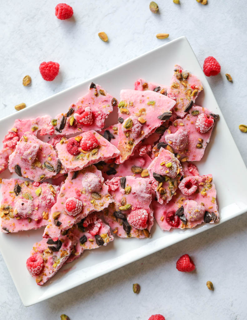 Plate with pieces of frozen yogurt bark covered in raspberries