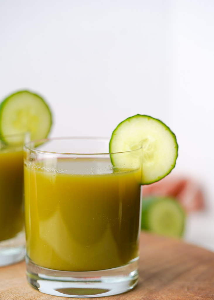 a cup of cucumber apple juice with sliced cucumber for garnish