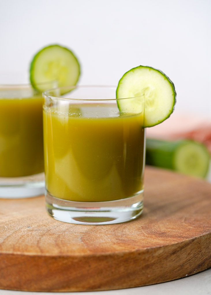 a cup of cucumber apple juice with sliced cucumber for garnish