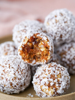 close up view of plated date balls with one bitten into to reveal the chewy center