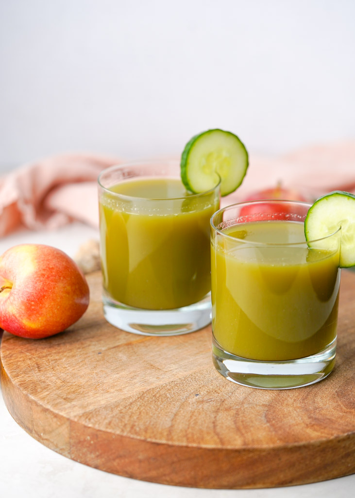 two cups of cucumber apple juice with sliced cucumbers for garnish