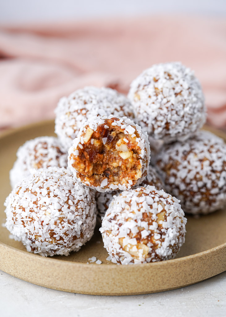 plated date energy balls with one bitten into to reveal the chewy center