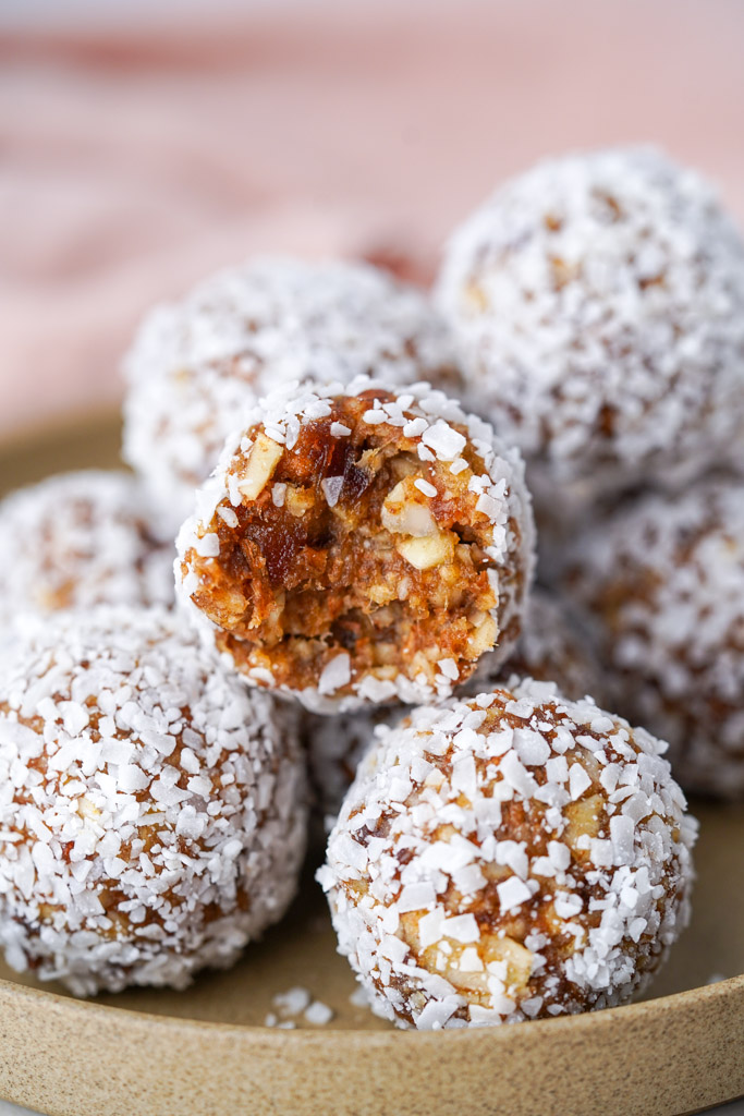 close up view of plated date balls with one bitten into to reveal the chewy center