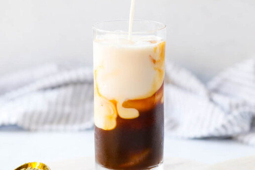 a pitcher pouring milk into a glass with espresso