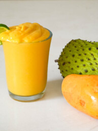 soursop smoothie in a glass garnished with lime wedge