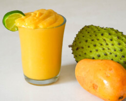 soursop smoothie in a glass garnished with lime wedge