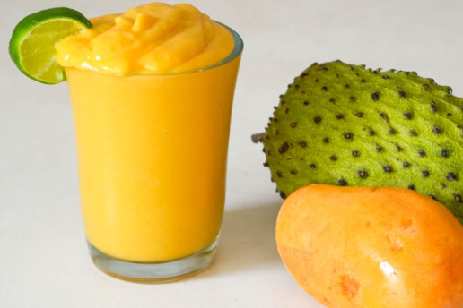 soursop smoothie in a glass garnished with lime wedge