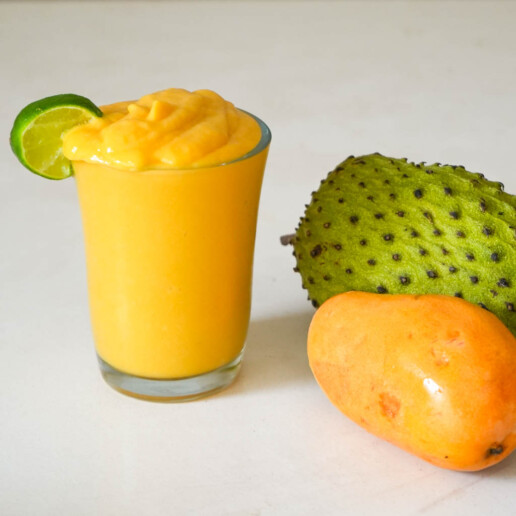 soursop smoothie in a glass garnished with lime wedge